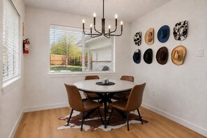 A dining area with a round table, four chairs, a cowhide rug, and a chandelier.