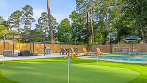 A backyard with a pool, a wooden fence, and a golf cart. - Spring Oasis: Heated Pool, Spa • Pickleball • Mini Golf • Basketball • Sleeps 12 (Spring)