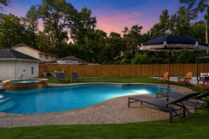 A backyard with a swimming pool, lounge chairs, and a wooden fence. - Spring Oasis: Heated Pool, Spa • Pickleball • Mini Golf • Basketball • Sleeps 12 (Spring)