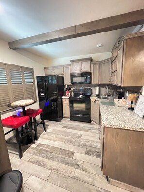 A kitchen with a refrigerator, stove, microwave, and wooden cabinets. - Cindy's Cozy Casita (Green Valley)