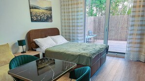A bedroom with a bed, a table, two chairs, a lamp, and a painting on the wall. - Nowy Dwór Mazowiecki Chic Studio (Nowy Dwór Mazowiecki)