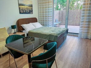 A bedroom with a bed, a table, two chairs, a lamp, and a painting on the wall. - Nowy Dwór Mazowiecki Chic Studio (Nowy Dwór Mazowiecki)