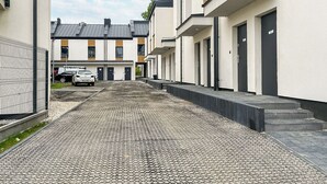 A residential street with cobblestone pavement, modern houses with balconies, and a parked car. - Nowy Dwór Mazowiecki Chic Studio (Nowy Dwór Mazowiecki)