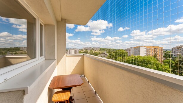 En balkon med udsigt over bybilledet, et bord og en stol.