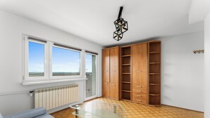 Et værelse med sofa, et glasbord, træskabe, en radiator og et vindue med udsigt.