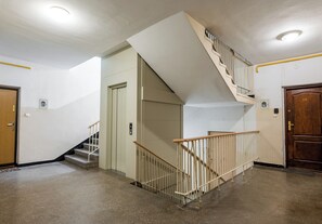 Eine Treppe mit hölzernem Geländer, eine Tür mit der Nummer 13 und einer Deckenleuchte.
