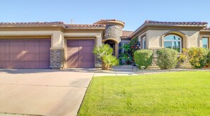 Front exterior of the home showcasing a multi-car garage, lawn, and stone accents. - Luxury La Quinta Retreat w/ Pool & Views (La Quinta)