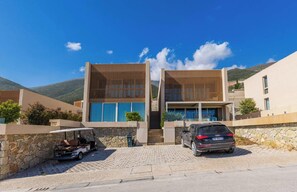 Ein modernes, zweistöckiges Haus mit Naturstein-Fassade, einem Auto auf der Auffahrt und einem Golfwagen.