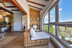 A cozy room with a wicker sofa, a lamp, and a view of greenery through large windows. - Miramar - By Almarina Villas (JÁVEA)