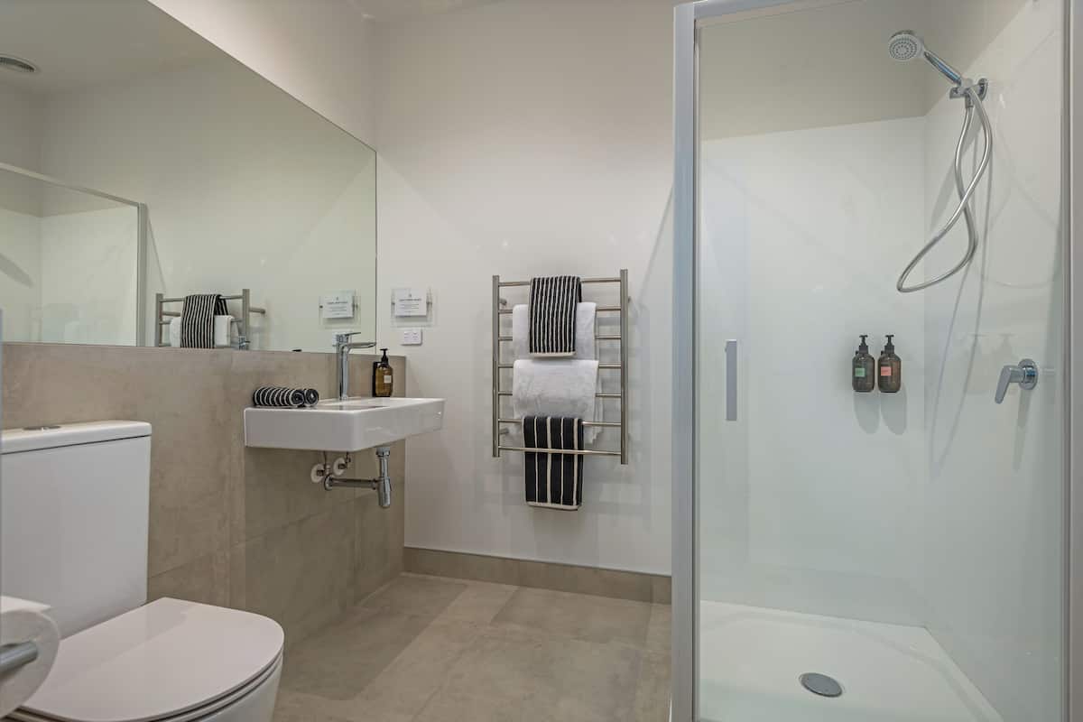 Un baño moderno con inodoro, lavamanos, toallero y ducha.