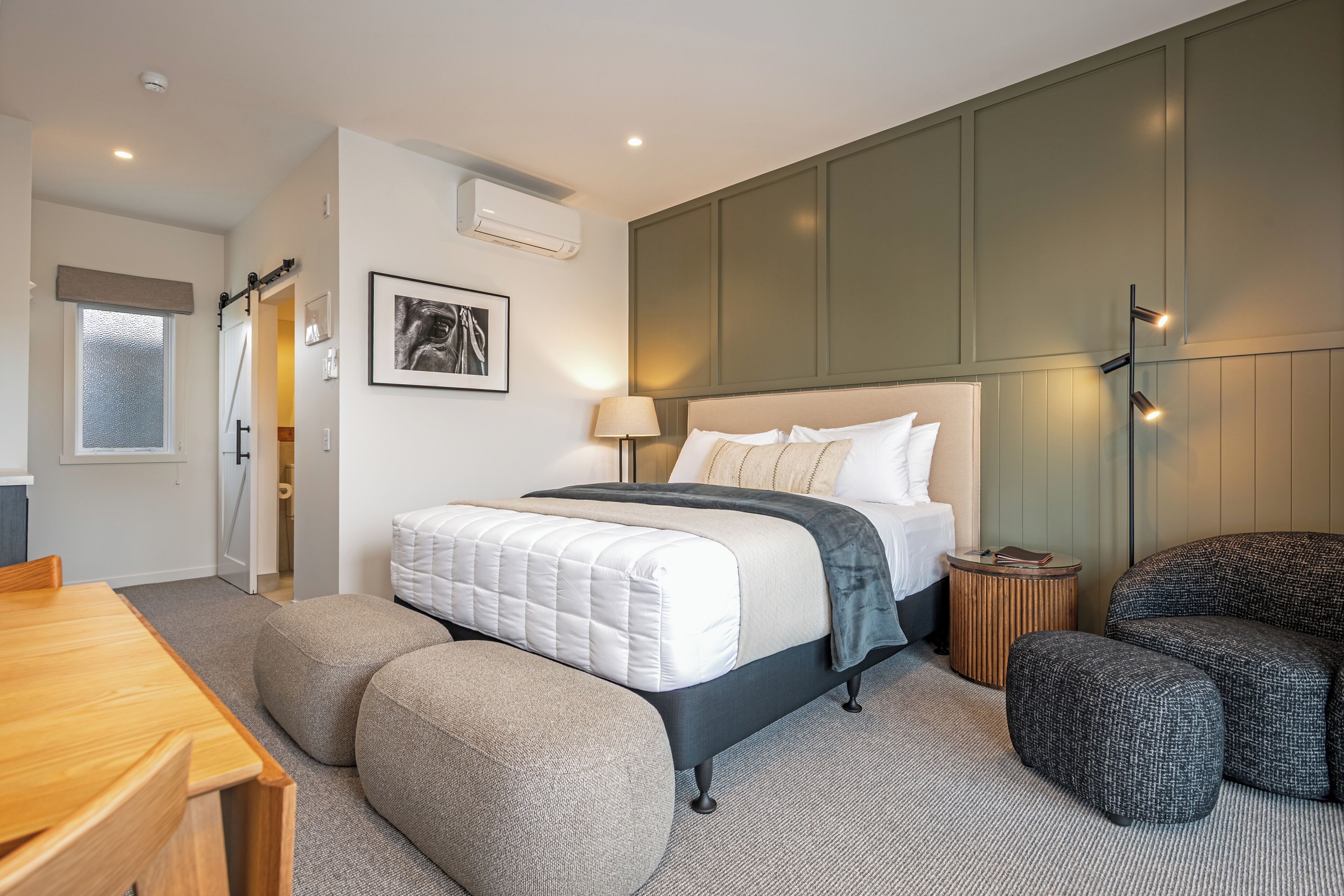 A modern bedroom with a bed, bedside table, and a seating area.