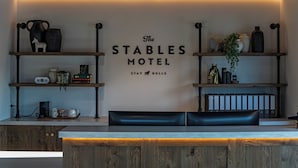 A reception desk with a sign reading 'The Stables Motel Stay Bull's' and shelves with various items.