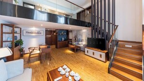 Amplia sala de estar con techo alto, una escalera y un televisor.