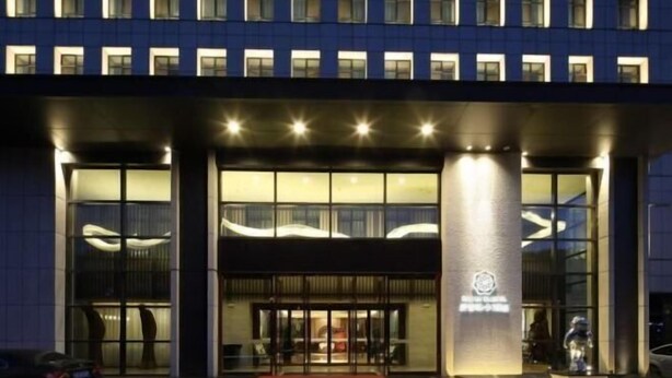 Una entrada de hotel con diseño moderno, amplias ventanas de vidrio y un logotipo destacado.
