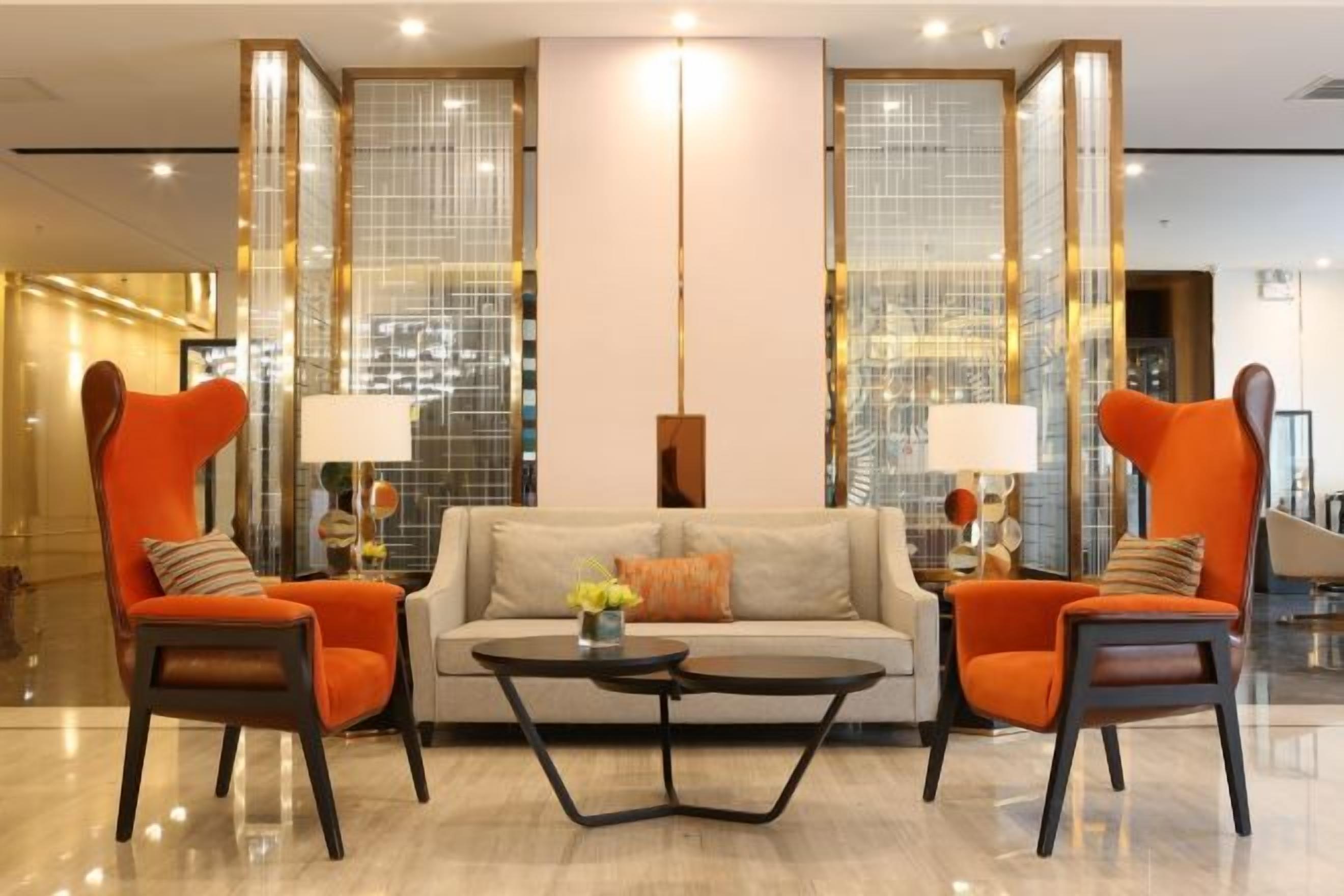 Eine moderne Lobby mit einer Couch, zwei Sesseln, einem Couchtisch und einer stehenden Stehlampe.