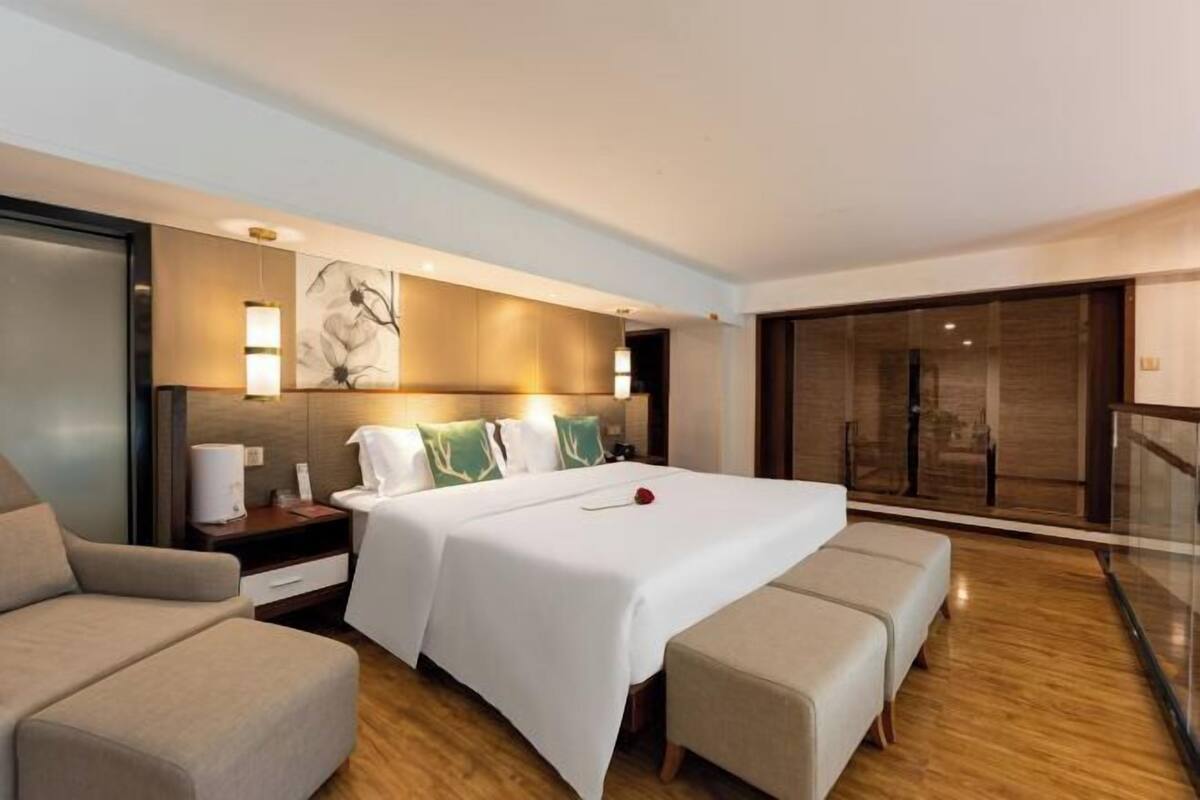 Una habitación de hotel con una cama grande, un sofá, un escritorio y un ventanal corredero al balcón.