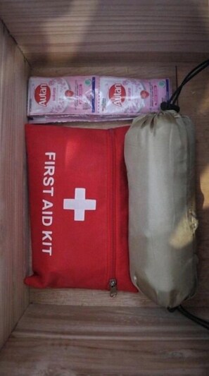 A wooden cabinet with a red first aid kit and a beige bag. - Lembah Tetebatu (Tetebatu)
