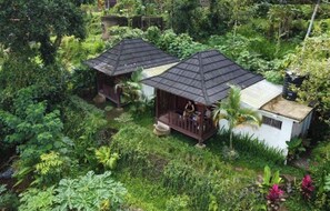 Two small, single-story structures with sloped roofs surrounded by dense tropical vegetation. - Lembah Tetebatu (Tetebatu)
