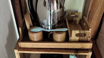 A wooden shelf with a kettle, a coffee pot, and a small appliance.