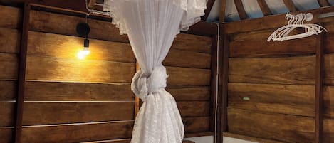 A bed with a canopy, wooden headboard, and pillows.