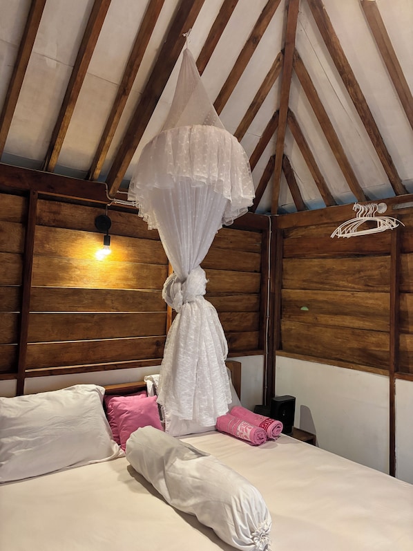 A bed with a canopy, wooden headboard, and pillows.