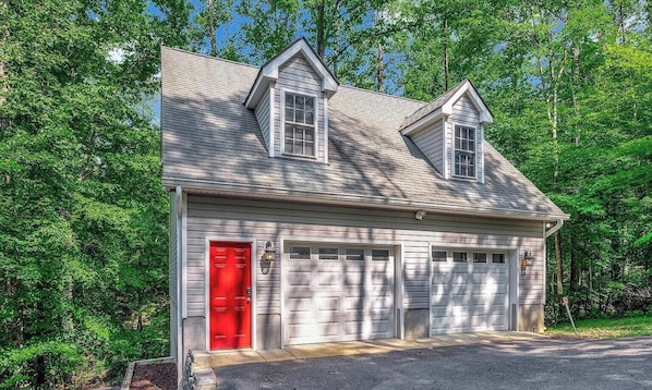 Una casa a un piano con una porta rossa, due porte garage e un tetto a spiovente.