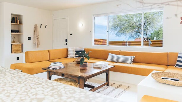 Ein modernes Wohnzimmer mit einer Couch, einem Couchtisch und Blick ins Freie durch ein großes Fenster.