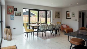 Un comedor moderno con una mesa grande, sillas y vista al jardín.