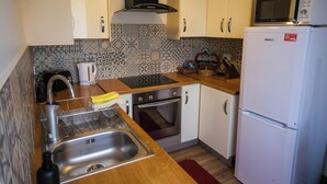 Una cocina con armarios blancos, microondas, horno y lavaplatos.