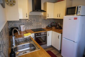 A kitchen with white cabinets, a microwave, an oven, and a sink.