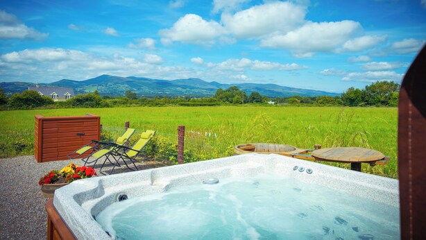 Un jacuzzi con vista a un campo verde y montañas.