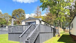 Una zona residencial con una casa de fachada gris, una escalera que conduce a la entrada y un patio cercado.