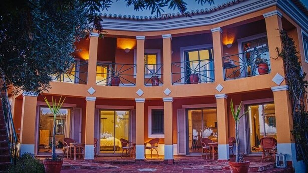 Un hotel de varios pisos con un patio central, balcones y ventanas amplias.