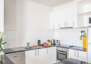 A modern kitchen with white cabinets, a black countertop, and a stove. - High Tech Living || Walking Distance City (Carlton)
