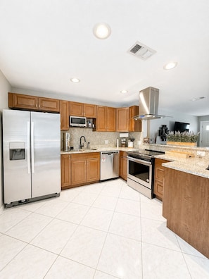 A modern kitchen with stainless steel appliances, wooden cabinets, and a granite countertop. - Brookside Oasis Leisure Bradenton Stay (Bradenton)