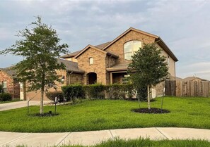 A two-story house with a brick exterior, a front porch, and a well-maintained lawn.
