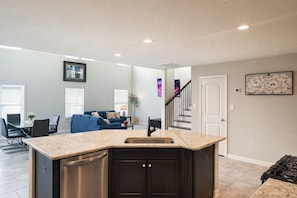 A modern kitchen with a granite countertop, dark cabinetry, and a stainless steel dishwasher.