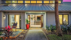 Ein modernes Haus mit Metalldach, einer Veranda und einem kleinen Garten.