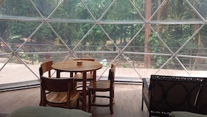 A room with a large glass window, a round wooden table, and four wooden chairs.