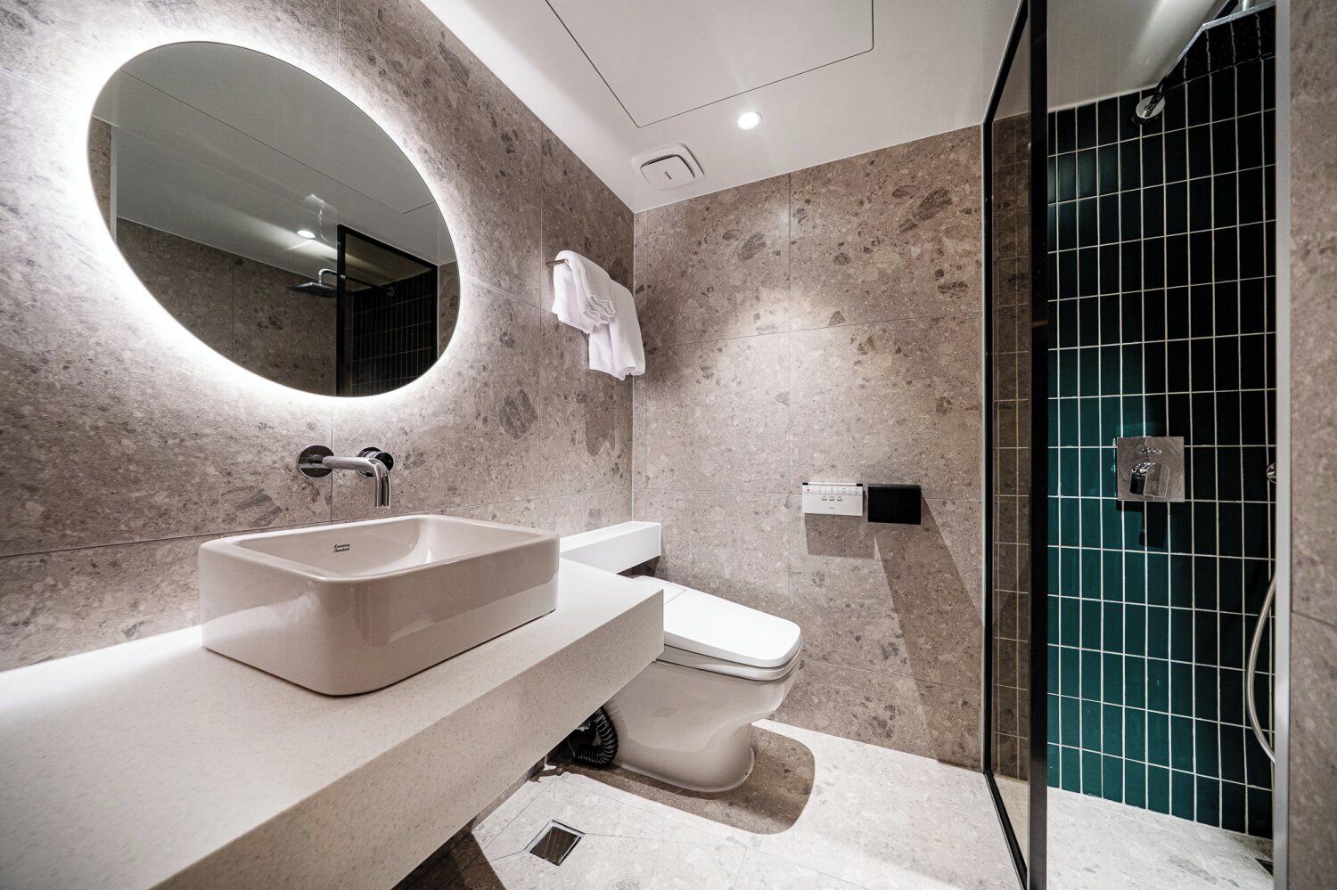 Un bagno moderno con un grande specchio ovale, un lavabo rettangolare e un water.