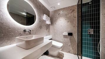 Un bagno moderno con un grande specchio ovale, un lavabo rettangolare e un water.