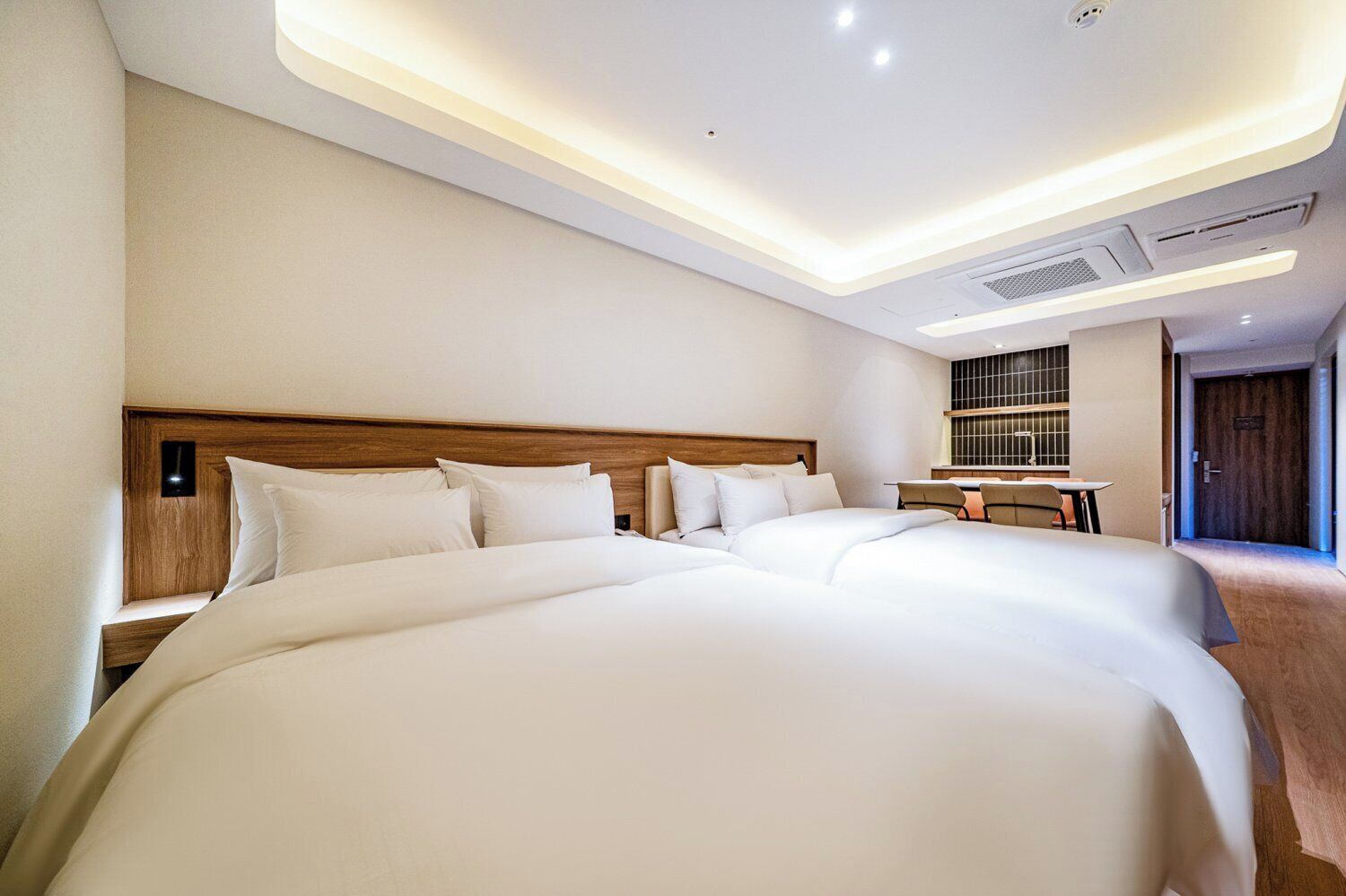 A hotel room with a large bed, bedside tables, a desk, and a window.