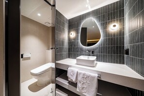 A modern bathroom with a toilet, sink, and mirror.