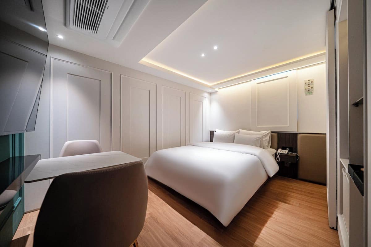 Una habitación de hotel moderna con cama, escritorio, silla y armario.