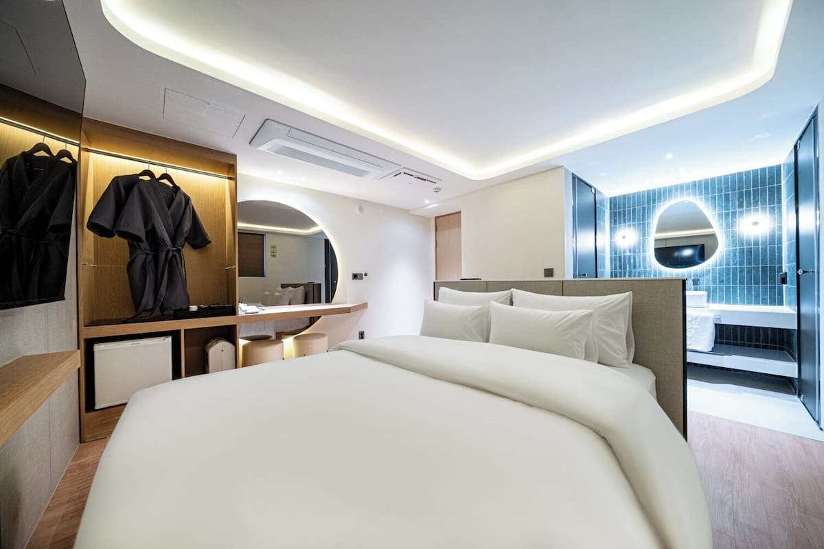 Una habitación de hotel moderna con una cama grande, un tocador con espejo y un escritorio con silla.