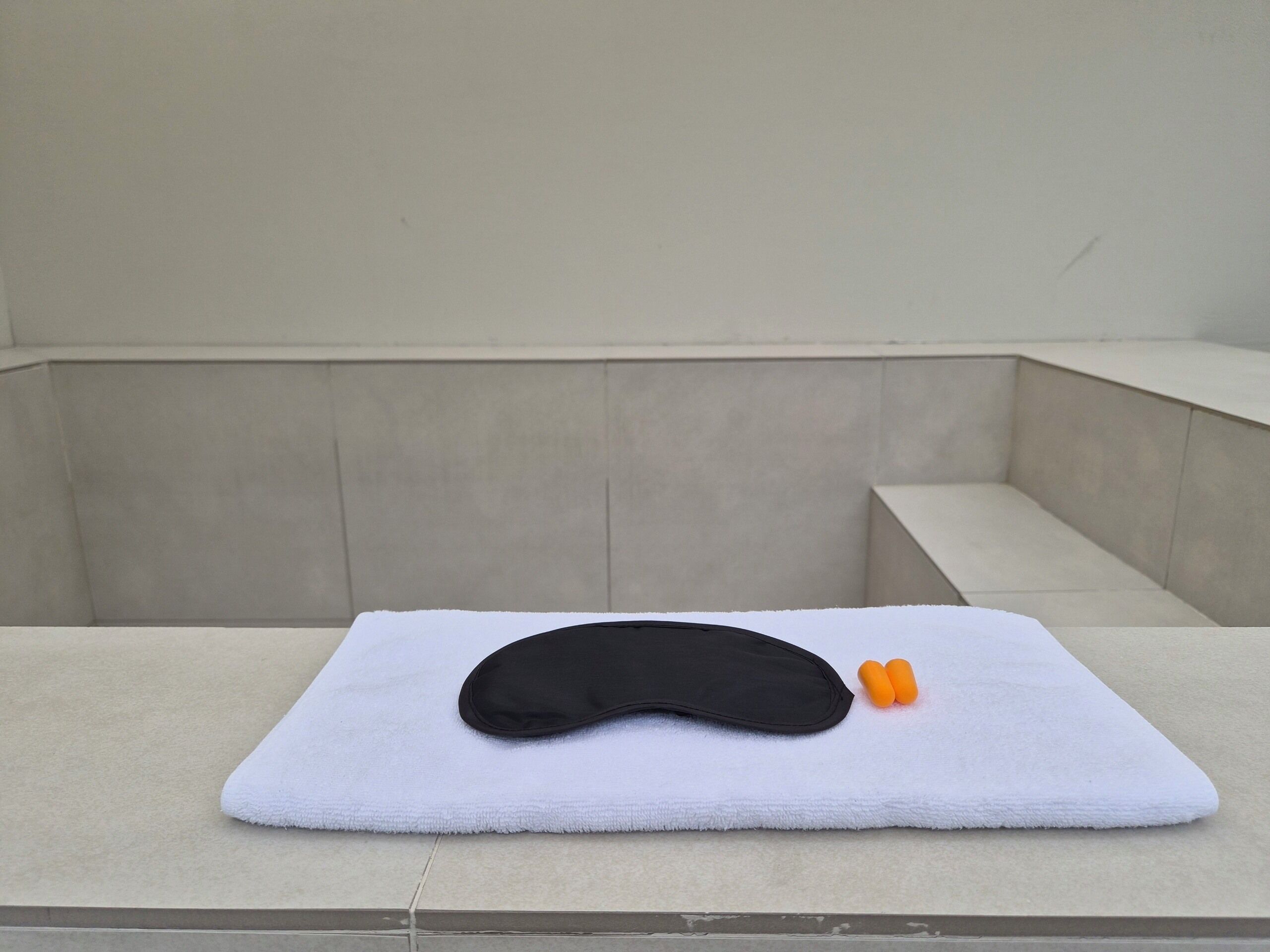 A white towel with a black object and two orange items on a tiled floor.