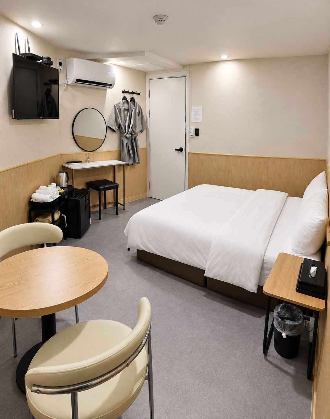 Ein Hotelzimmer mit Bett, Schreibtisch, Stuhl, Tisch, Klimaanlage und Fernseher.