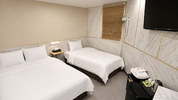 A hotel room with two beds, a desk, a TV, and a minibar.