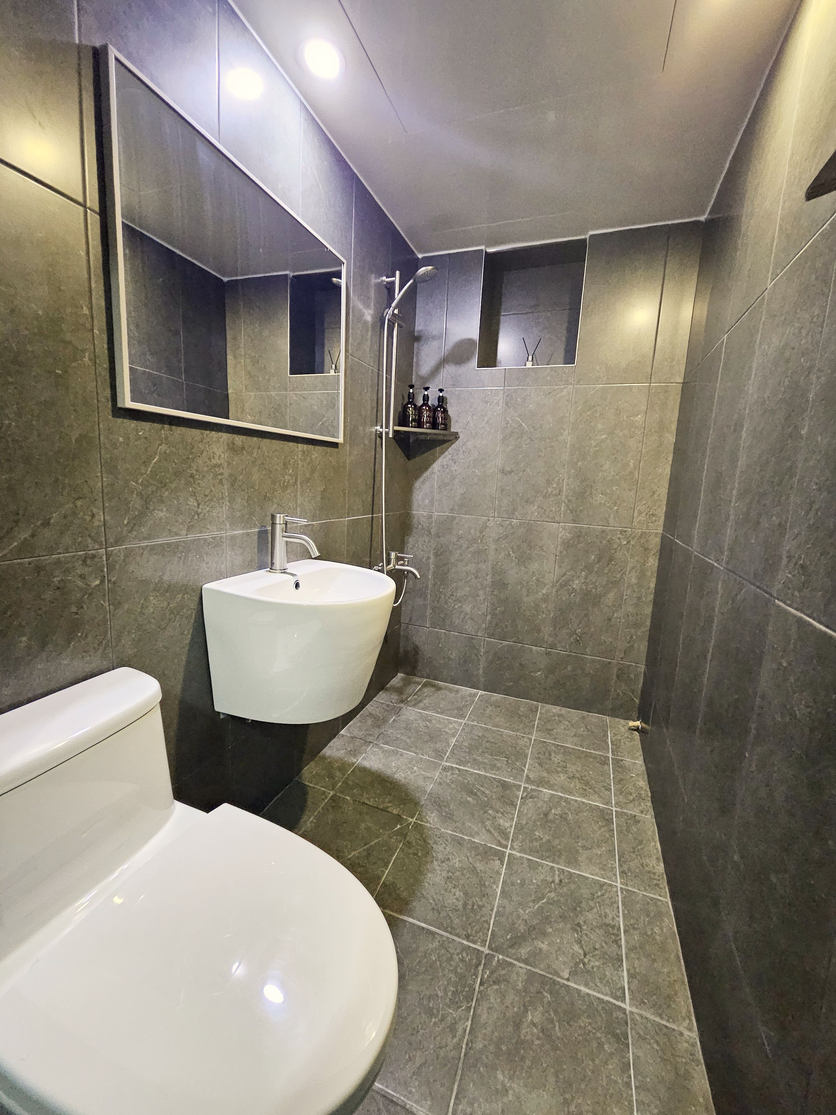 A modern bathroom with a white sink, a toilet, and a shower area.