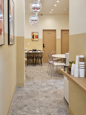 A hotel corridor with a dining area, two staff-only doors, and a counter with stacked cups. - Cheonho T Hotel (Seoul)